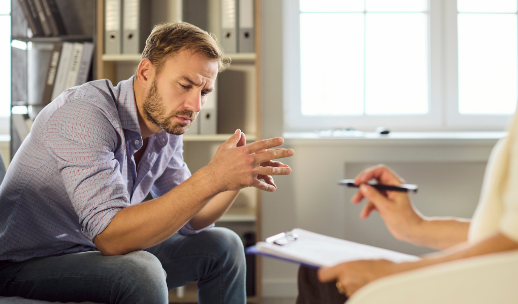 a Man sitting on a couch during a mental health therapy session with a therapist